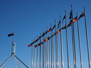 Australian flags fly outside Parliament House, representing issues of inequality and Indigenous rights.