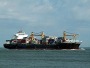 A large container ship approaches a port, illustrating global data transfer for business news.