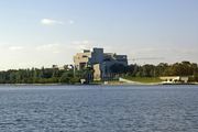 The High Court of Australia building and an international flag display are visible across Lake Burley Griffin, relating to a.